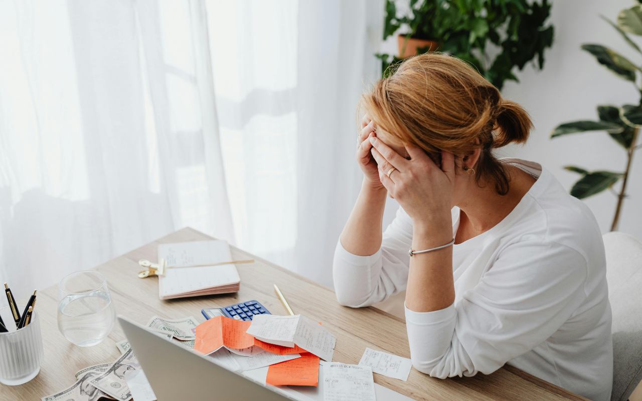 Žena sedi za stolom i drži se za glavu